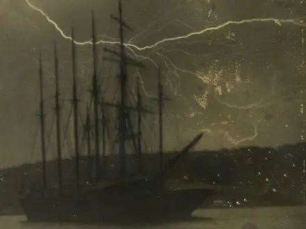 An very old picture of a ship on a stormy day with lightning in the background