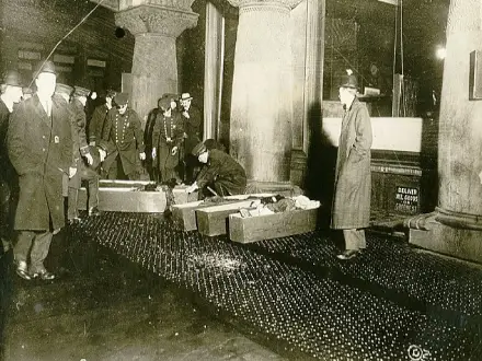 A dark room with a couple of men inspecting some coffins